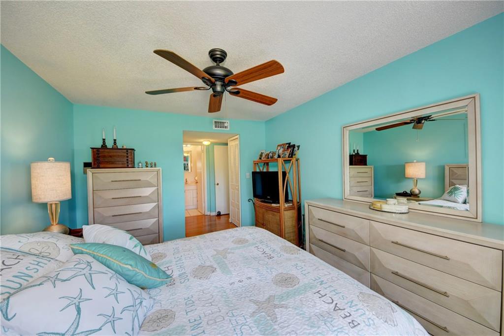 5433 Southeast Miles Grant Road, Unit E203 Stuart, FL 34997 - Photo 17 of 42 a bedroom with a bed and a chandelier