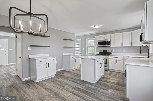 a kitchen with white cabinets stainless steel appliances and a chandelier