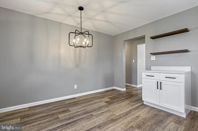 a view of an empty room with wooden floor and window