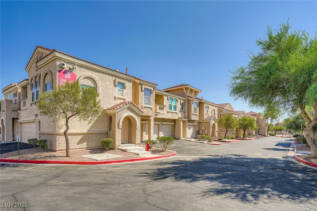 10550 West Alexander Road, Unit 2219 Las Vegas, NV 89129 - Photo 5 of 29 View of building exterior with a residential view, a garage, and driveway