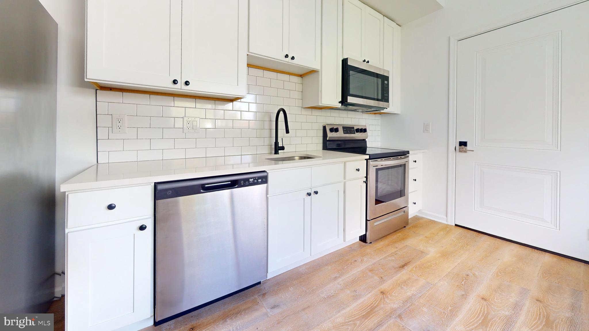 a kitchen with stainless steel appliances granite countertop a stove a sink and a microwave