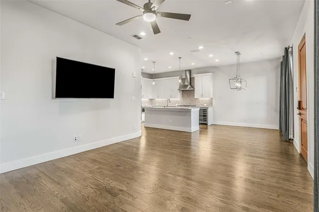 an empty room with wooden floor cabinet and windows