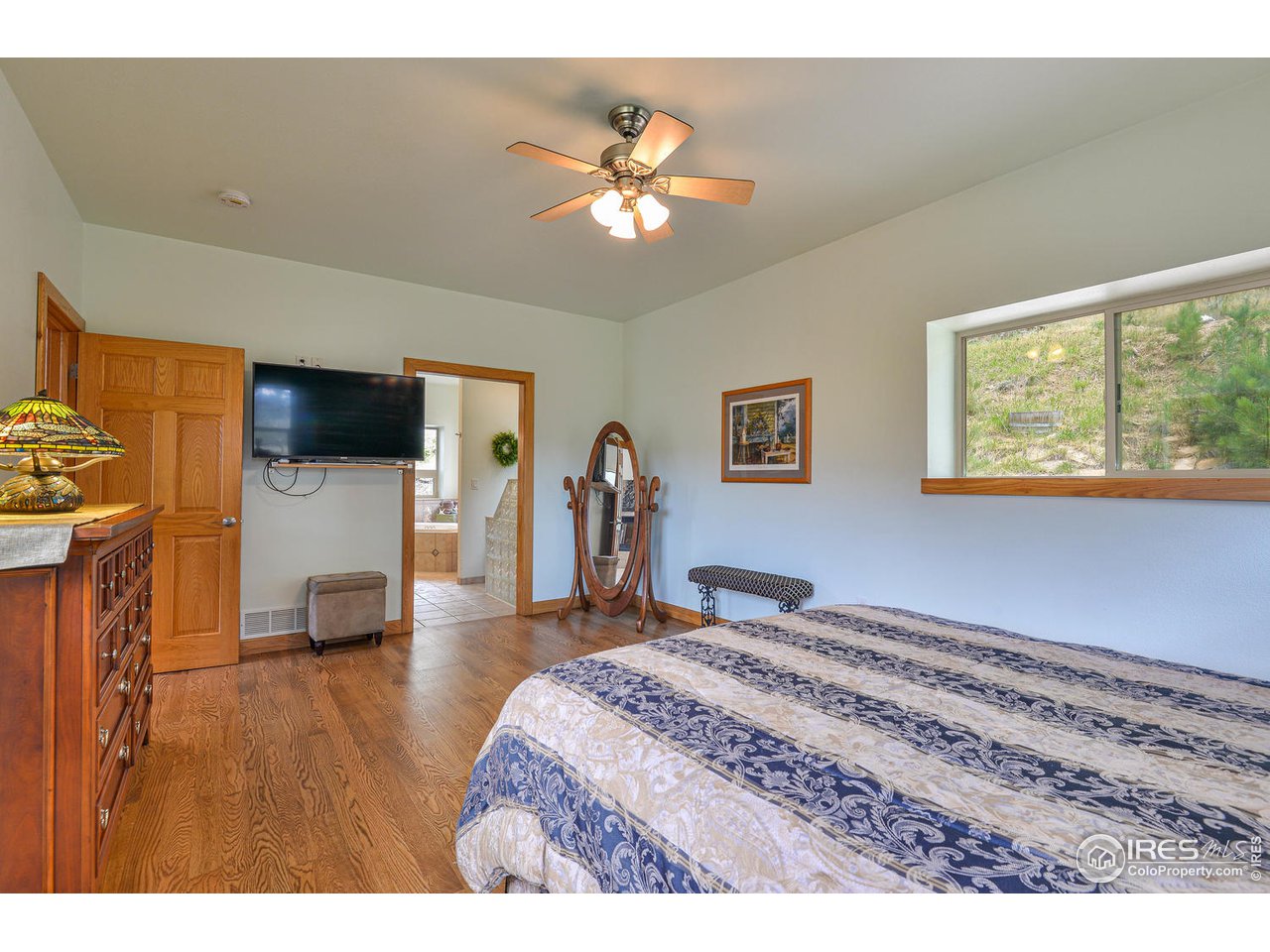 560 Stove Prairie Road Bellvue, CO 80512 - Photo 16 of 40 a bedroom with a bed and a flat tv screen on dresser