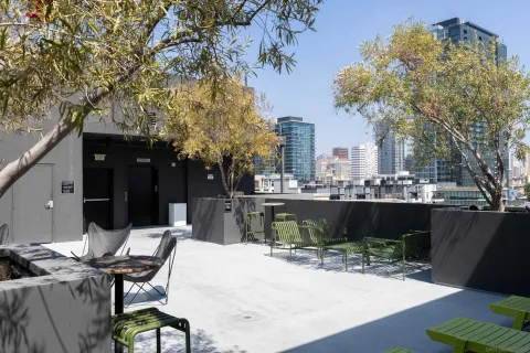 a roof deck with table and chairs and potted plants