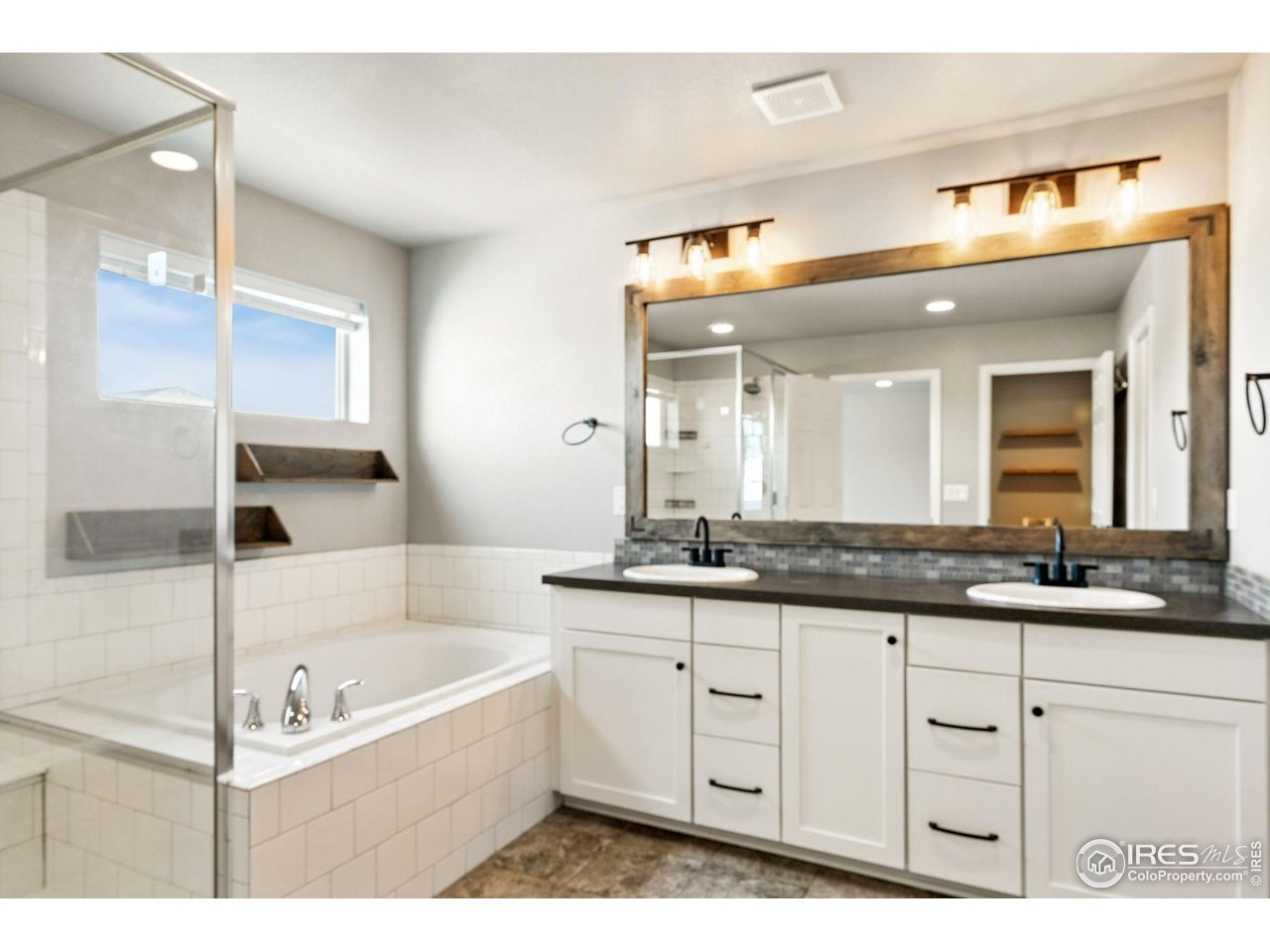 6420 Tuxedo Park Road Timnath, CO 80547 - Photo 15 of 44 a bathroom with a granite countertop sink mirror and a bathtub
