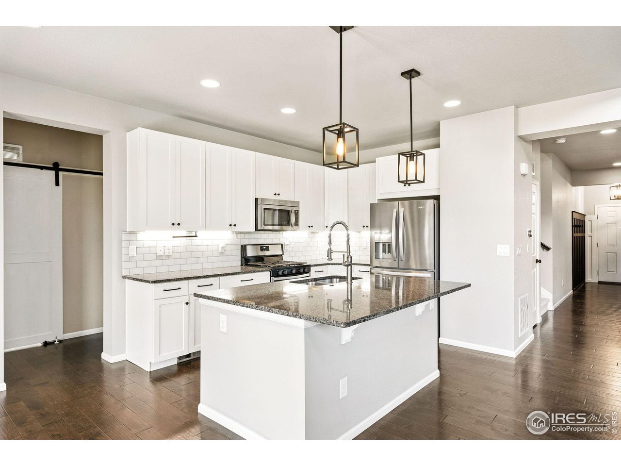 6420 Tuxedo Park Road Timnath, CO 80547 - Photo 4 of 44 a kitchen with stainless steel appliances granite countertop a sink a refrigerator and a wooden floor