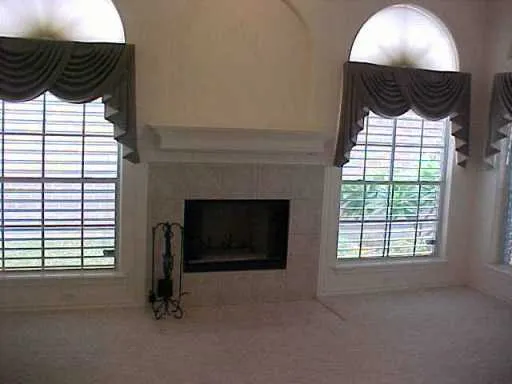 a view of an empty room with a fireplace and a window