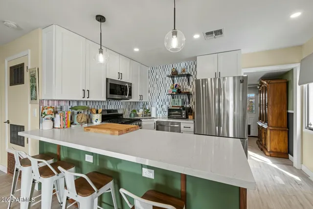 a kitchen with stainless steel appliances kitchen island granite countertop a refrigerator a stove and a sink with wooden floor