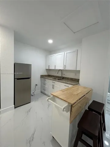 a kitchen with a sink a stove a refrigerator and white cabinets