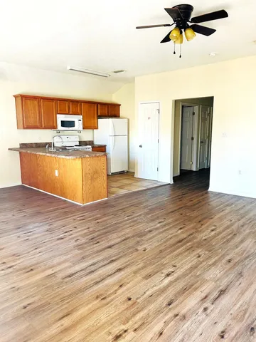 a view of a room with kitchen and wooden floor