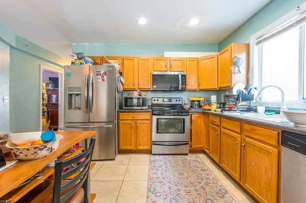 a kitchen with stainless steel appliances kitchen island granite countertop a refrigerator and a stove top oven