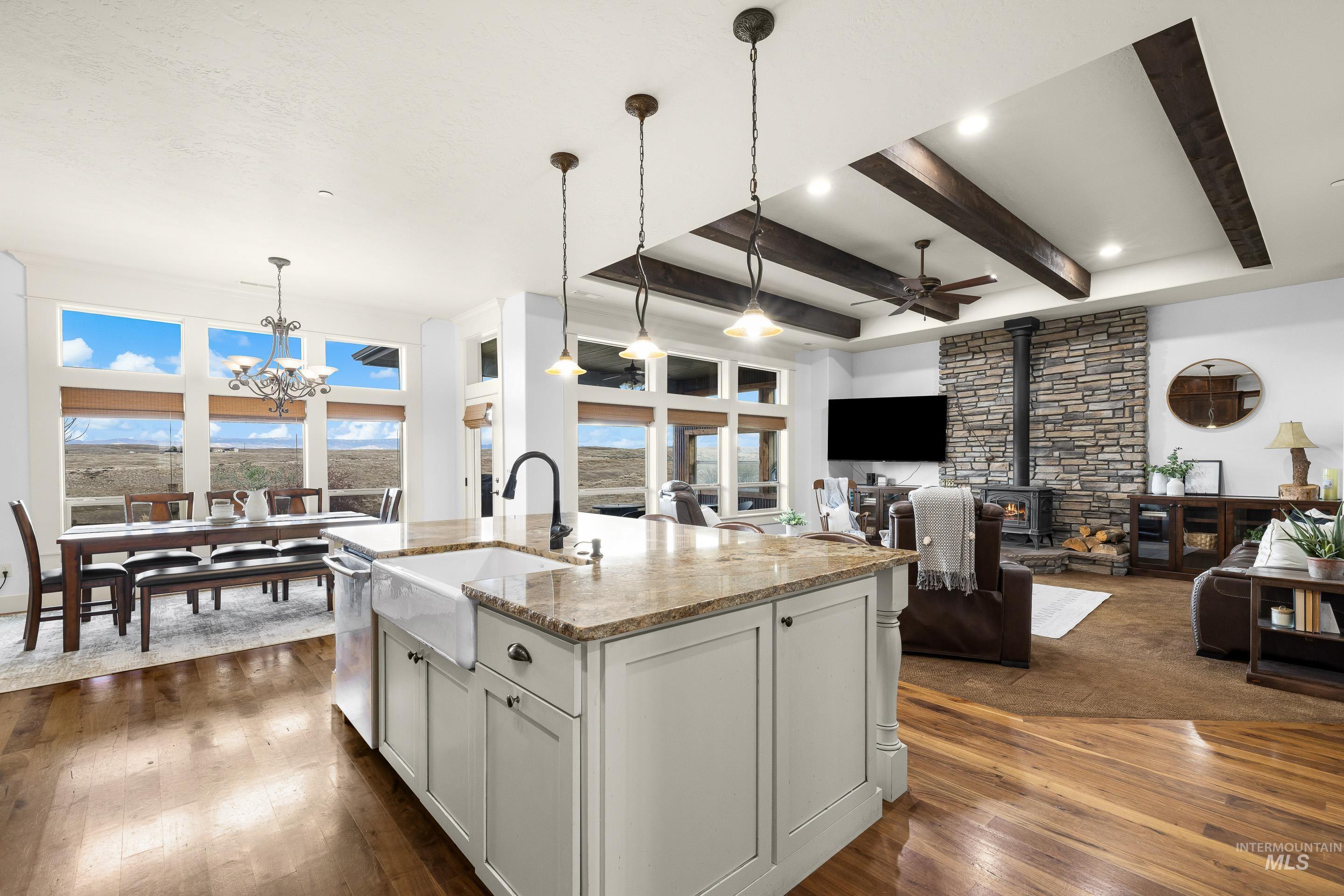 7521 North Grand Ridge Lane Eagle, ID 83616 - Photo 15 of 50 Kitchen with light stone countertops, dark wood finished floors, white cabinets, ceiling fan, and a kitchen island with sink