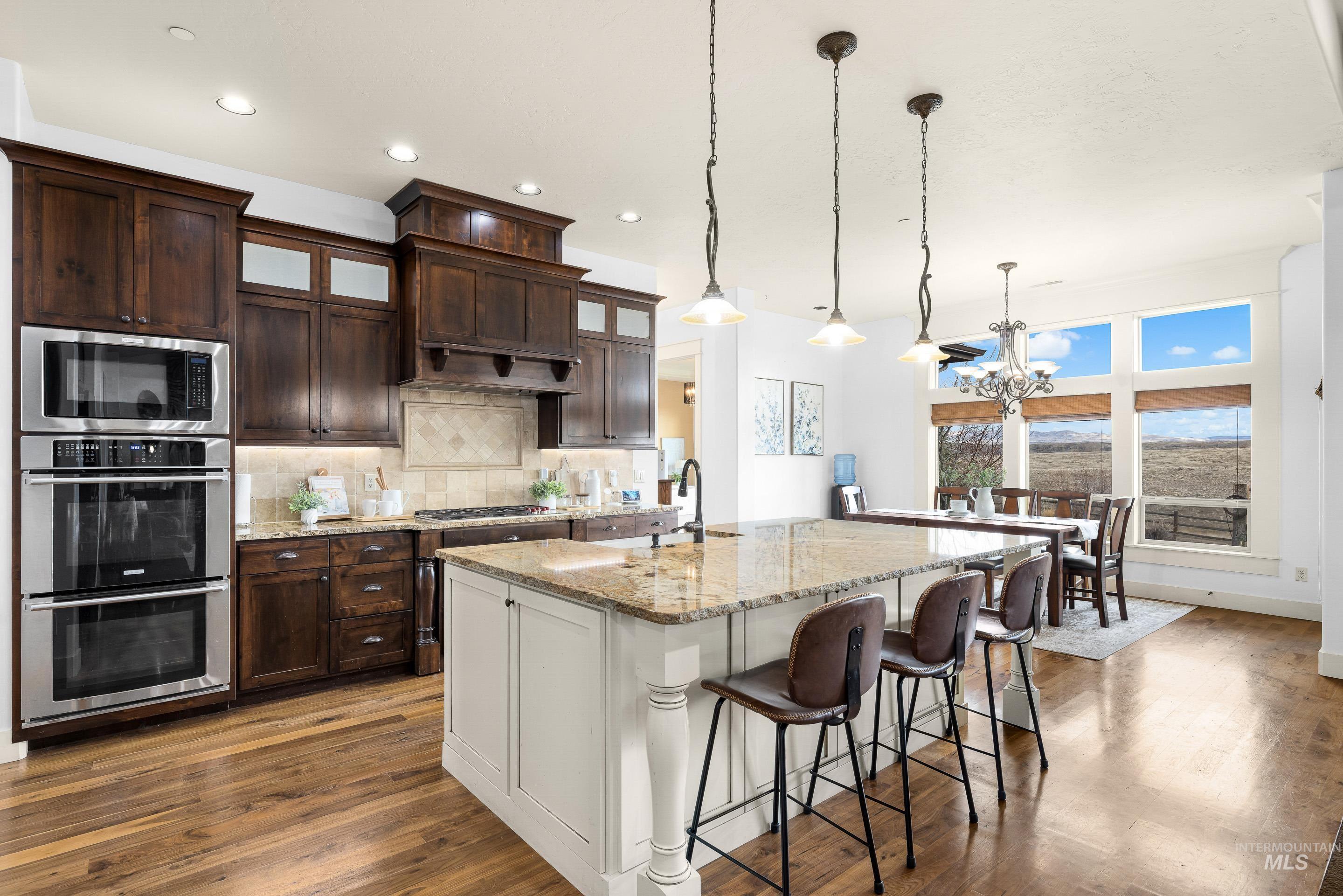 7521 North Grand Ridge Lane Eagle, ID 83616 - Photo 17 of 50 Two tone kitchen featuring two tone color scheme, glass fronted cabinets, light stone countertops, stainless steel appliances, and decorative backsplash