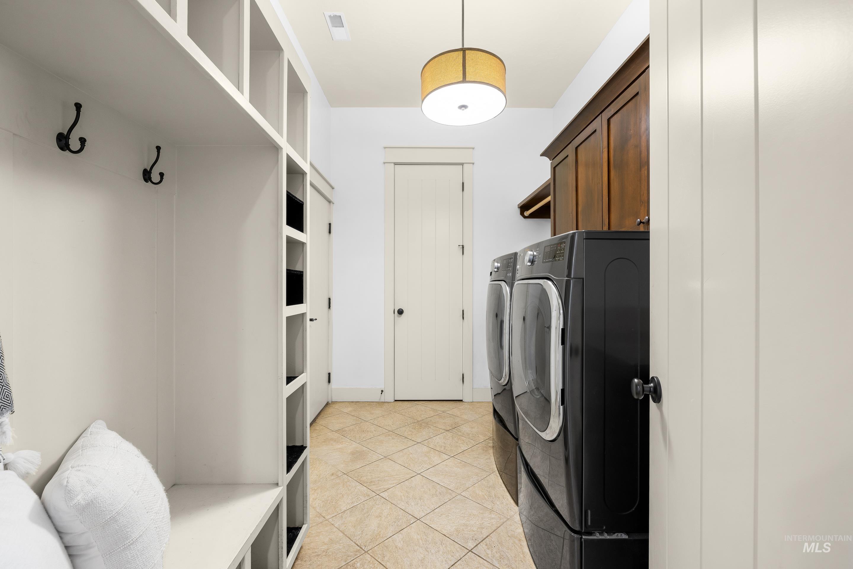 7521 North Grand Ridge Lane Eagle, ID 83616 - Photo 38 of 50 Laundry room with light tile patterned floors, washer and clothes dryer, and cabinet space