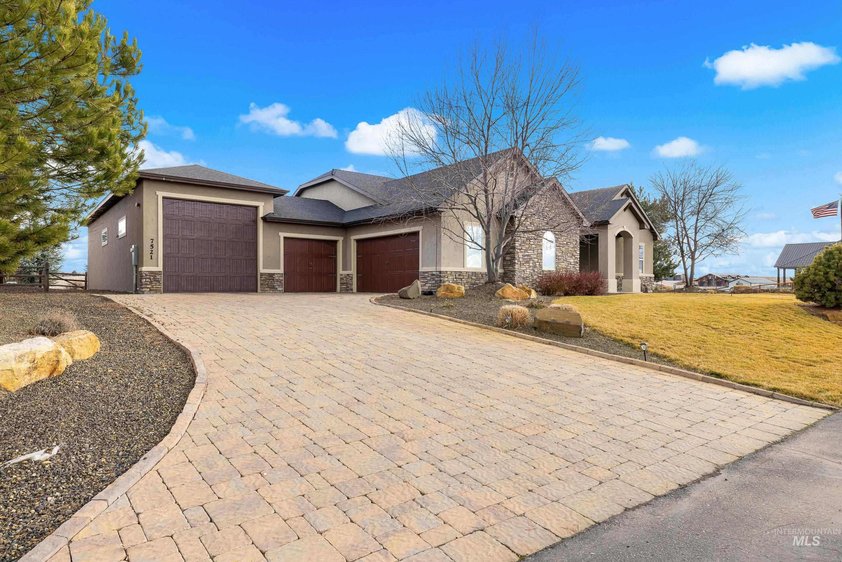 7521 North Grand Ridge Lane Eagle, ID 83616 - Photo 4 of 50 View of front of home with stone siding, stucco siding, a garage, decorative driveway, and a front yard