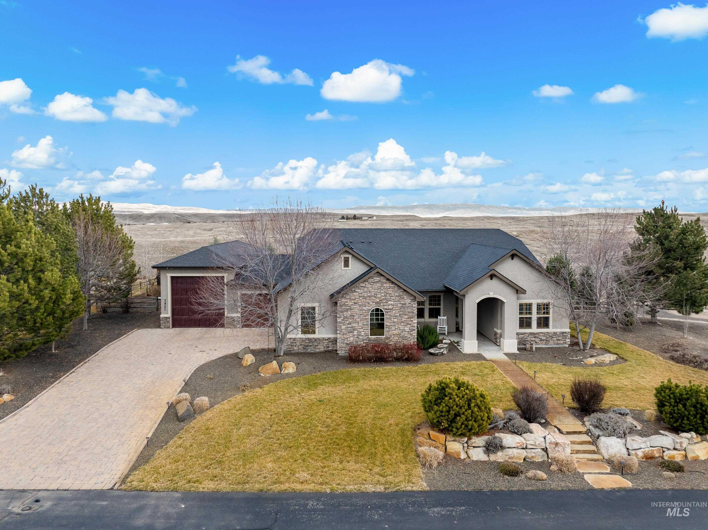 7521 North Grand Ridge Lane Eagle, ID 83616 - Photo 47 of 50 Single story home with stone siding, decorative driveway, a front yard, a garage, and stucco siding
