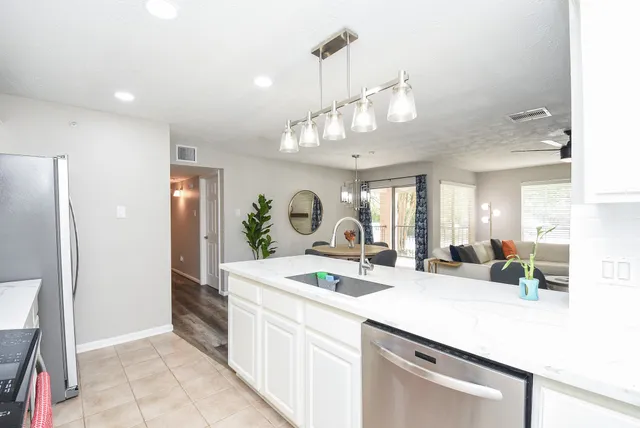 a kitchen with a sink dishwasher a dining table and chairs with wooden floor