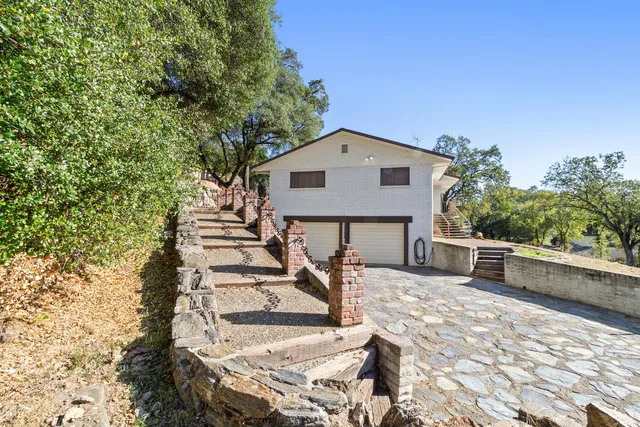 a front view of a house with large trees