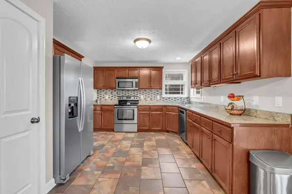 a kitchen with stainless steel appliances granite countertop a refrigerator stove and sink
