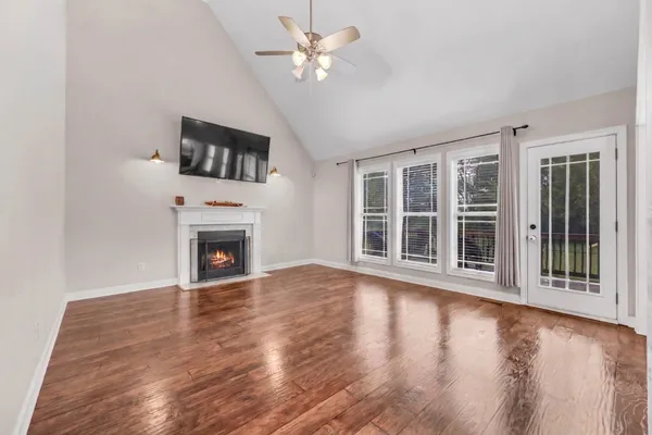 a view of an empty room with wooden floor and a fireplace