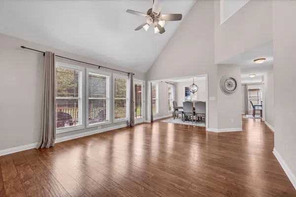 a view of an empty room with wooden floor and a ceiling fan