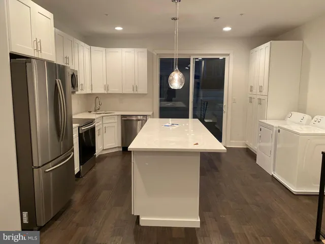 a kitchen with a refrigerator a sink and dishwasher with wooden floor