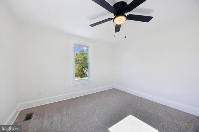 an empty room with a window and a ceiling fan