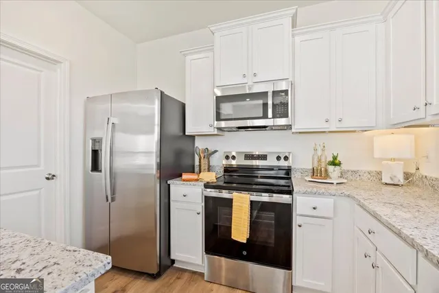 a kitchen with stainless steel appliances granite countertop a refrigerator stove and white cabinets