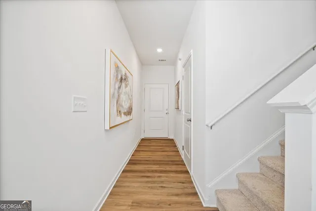 a view of a hallway with wooden floor and stairs