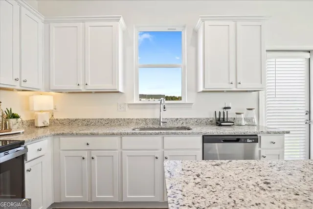 a kitchen with granite countertop white cabinets and sink
