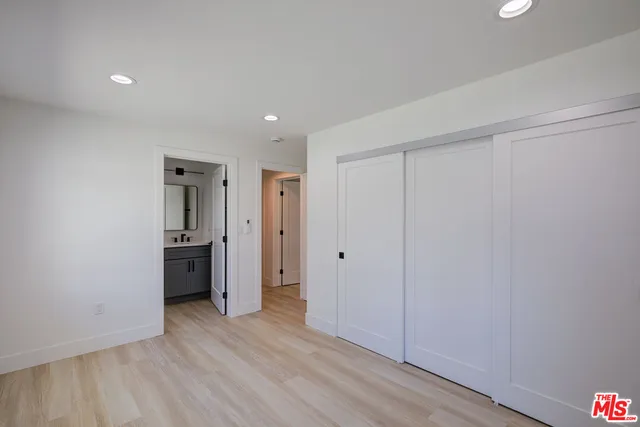 a view of a hallway with wooden floor and a kitchen
