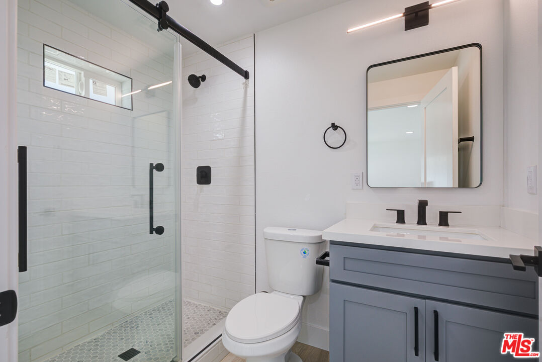 1303 Beryl Street Redondo Beach, CA 90277 - Photo 13 of 31 a bathroom with a toilet a sink a glass door a shower a mirror and vanity