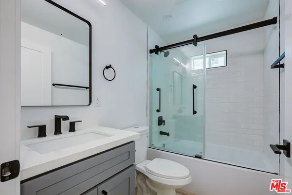 a bathroom with a toilet a sink a mirror a vanity and shower