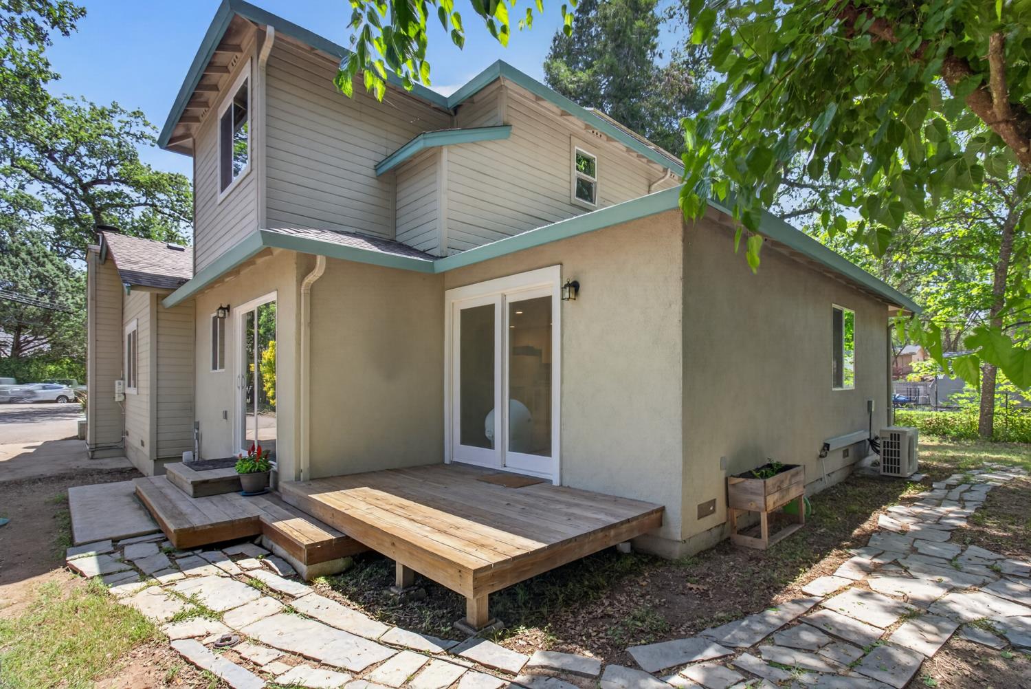 6332 Horseshoe Bar Road Loomis, CA 95650 - Photo 68 of 85 Rear exterior featuring a ground-level wood deck, stone pathway, stucco and siding finishes, and multiple glass sliding doors