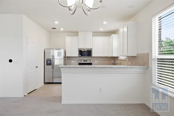 a kitchen with stainless steel appliances granite countertop a refrigerator a stove a sink and a microwave