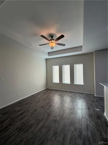 an empty room with wooden floor and a ceiling fan