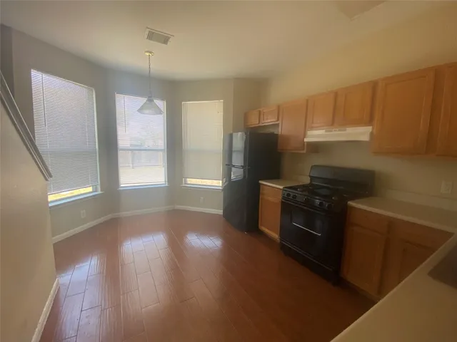 a kitchen with granite countertop a refrigerator and a stove top oven
