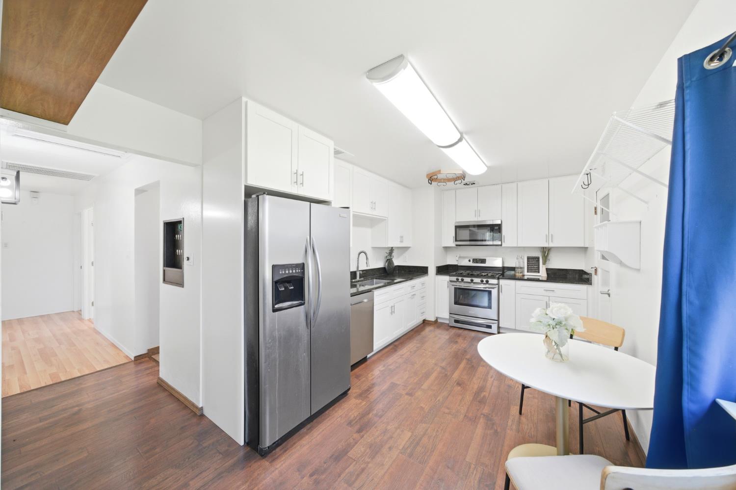 6515 West 4th Street Rio Linda, CA 95673 - Photo 23 of 97 a kitchen with stainless steel appliances a refrigerator a stove a sink dishwasher a dining table and chairs with wooden floor