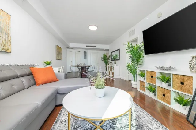 a living room with furniture a flat screen tv and a floor to ceiling window