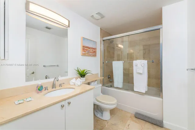a bathroom with a granite countertop sink a toilet a mirror a vanity and shower