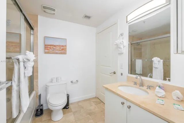 a bathroom with a granite countertop sink mirror vanity and toilet