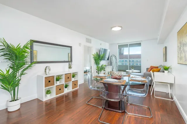 a dining room with wooden floor a chandelier a glass table and chairs