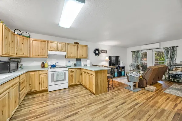 a kitchen with granite countertop a stove top oven a sink dishwasher a dining table and chairs with wooden floor