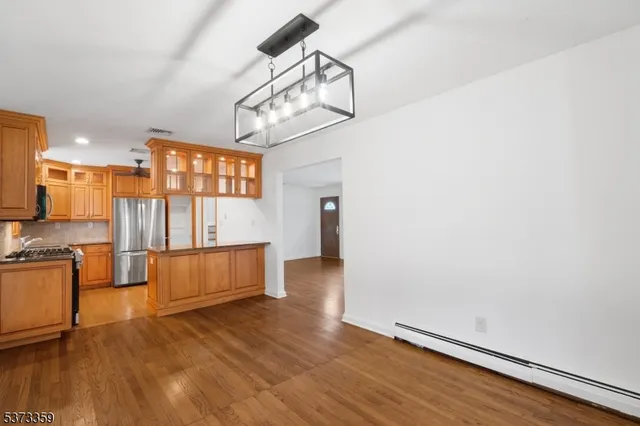 a view of an empty room with kitchen and a window