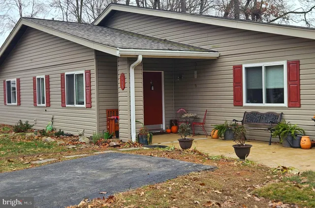 a view of a house with a wooden bench in a backyard