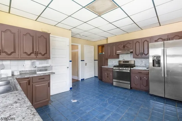 a kitchen with stainless steel appliances granite countertop a refrigerator a sink dishwasher a stove with wooden cabinets