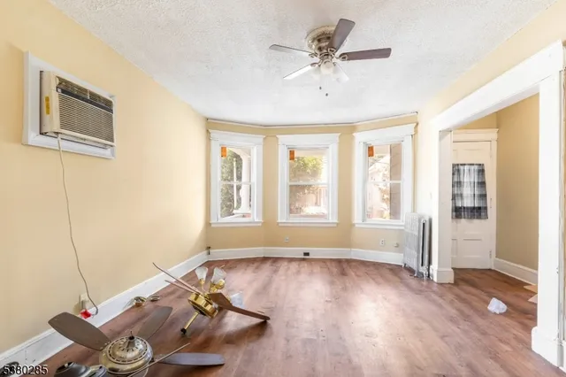 a view of an empty room with a window and wooden floor