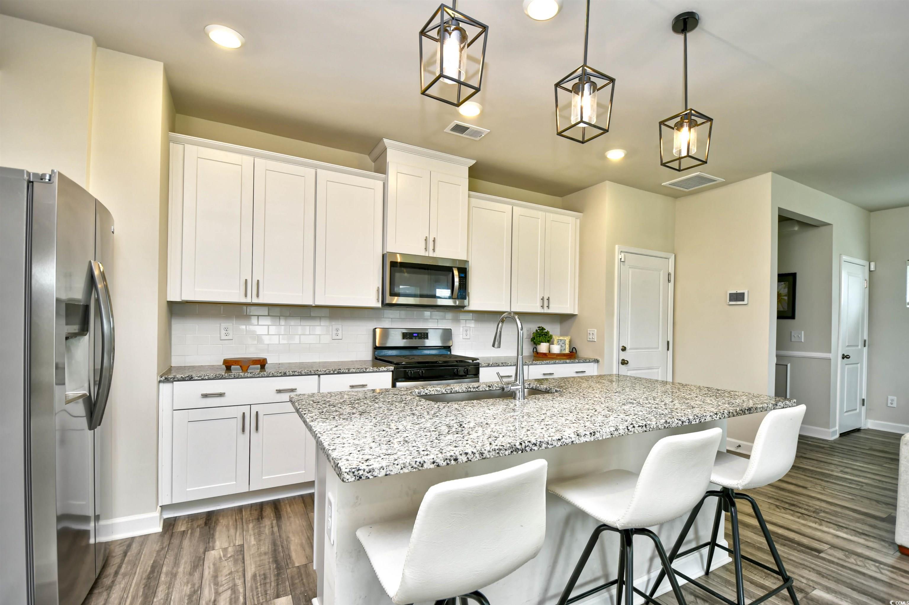 2325 Copper Crk Loop Longs, SC 29568 - Photo 12 of 40 Kitchen with appliances with stainless steel finishes, white cabinetry, light stone counters, a breakfast bar, and recessed lighting