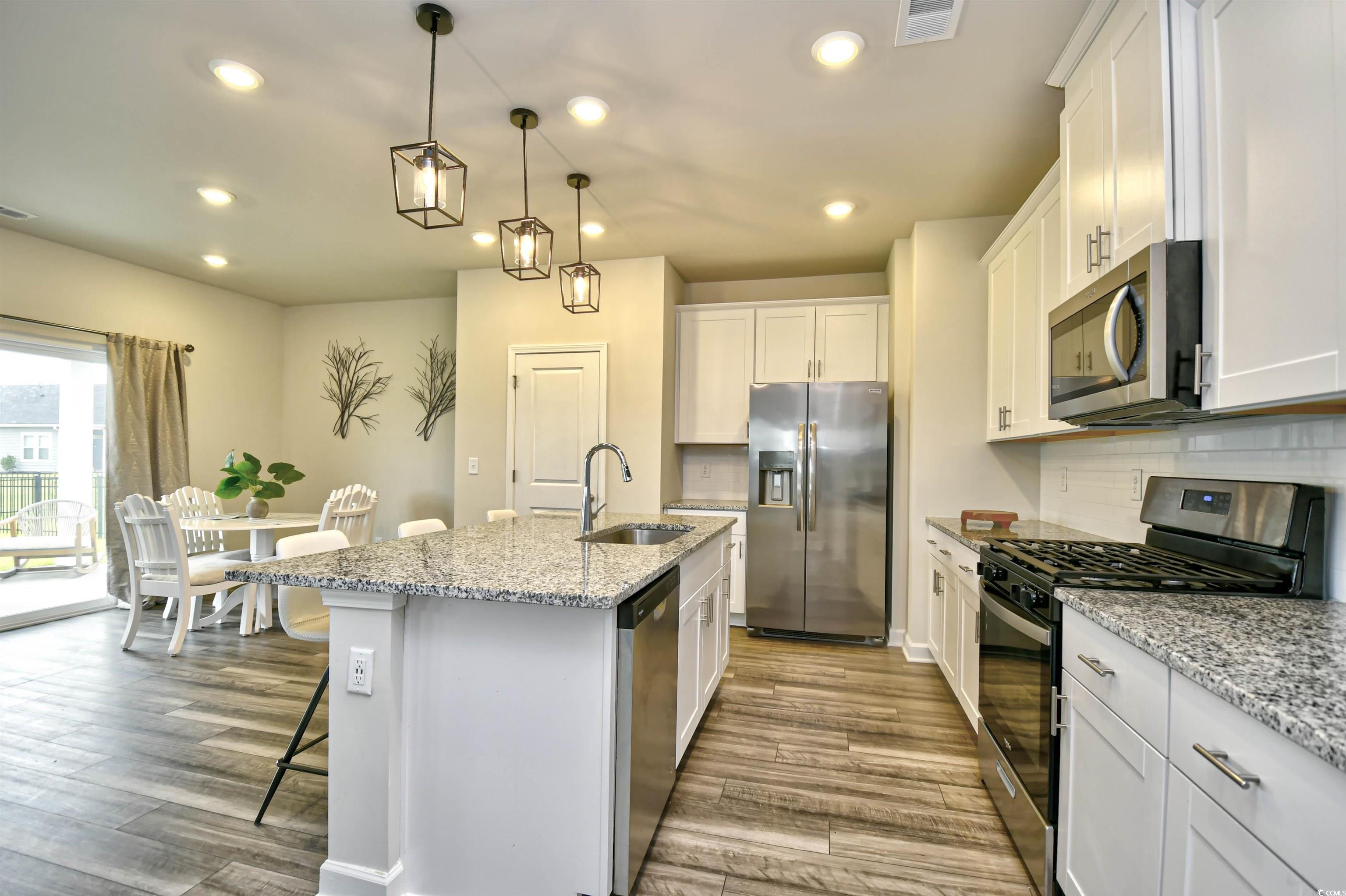 2325 Copper Crk Loop Longs, SC 29568 - Photo 13 of 40 Kitchen with appliances with stainless steel finishes, light stone counters, hanging light fixtures, a center island with sink, and recessed lighting