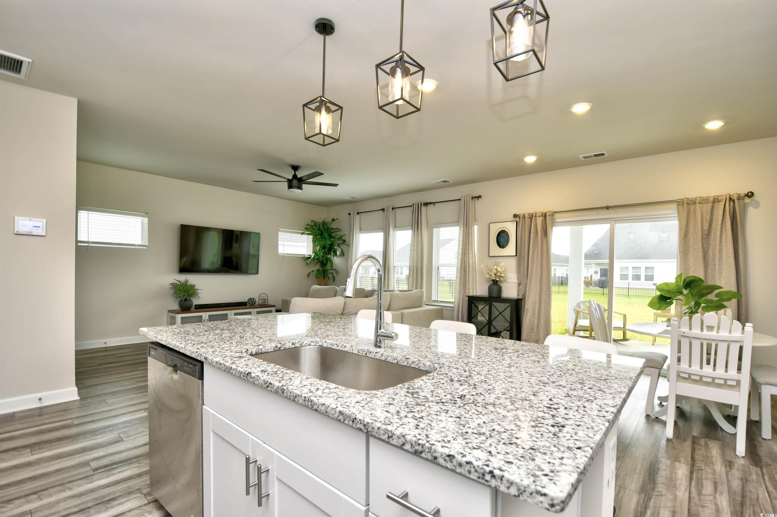 2325 Copper Crk Loop Longs, SC 29568 - Photo 14 of 40 Kitchen with light stone counters, white cabinetry, stainless steel dishwasher, a kitchen island with sink, and plenty of natural light